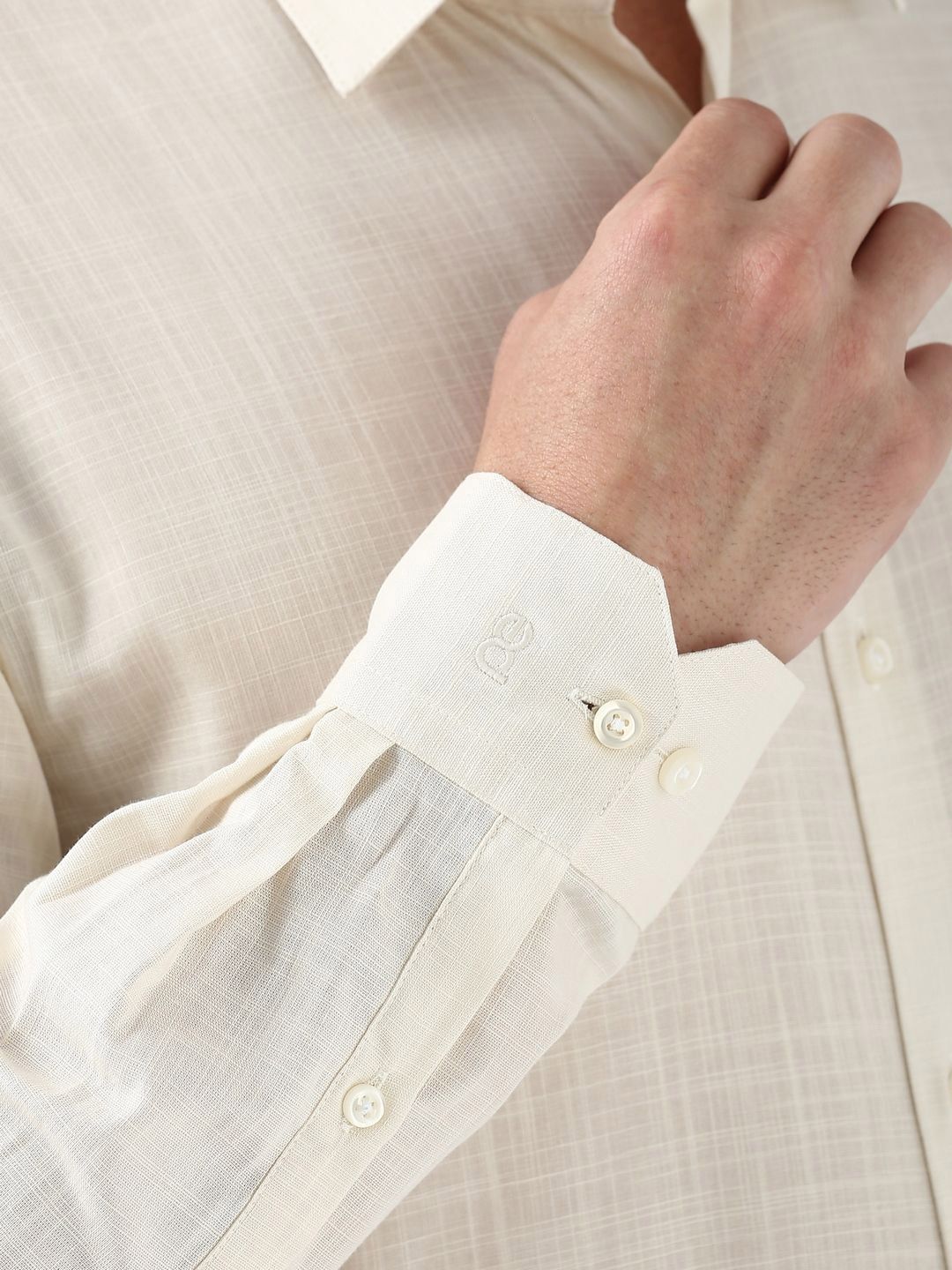 Close-up of a person wearing a light-colored shirt with a sheer overlay.