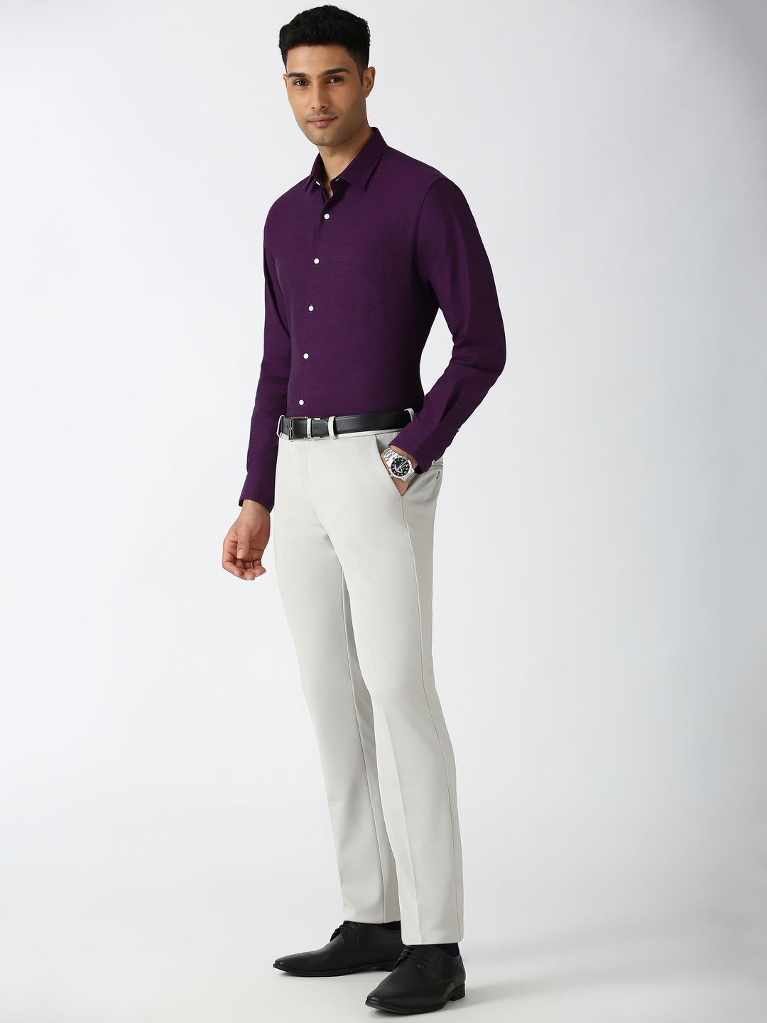 Man wearing a purple shirt, white pants, and black shoes on a white background