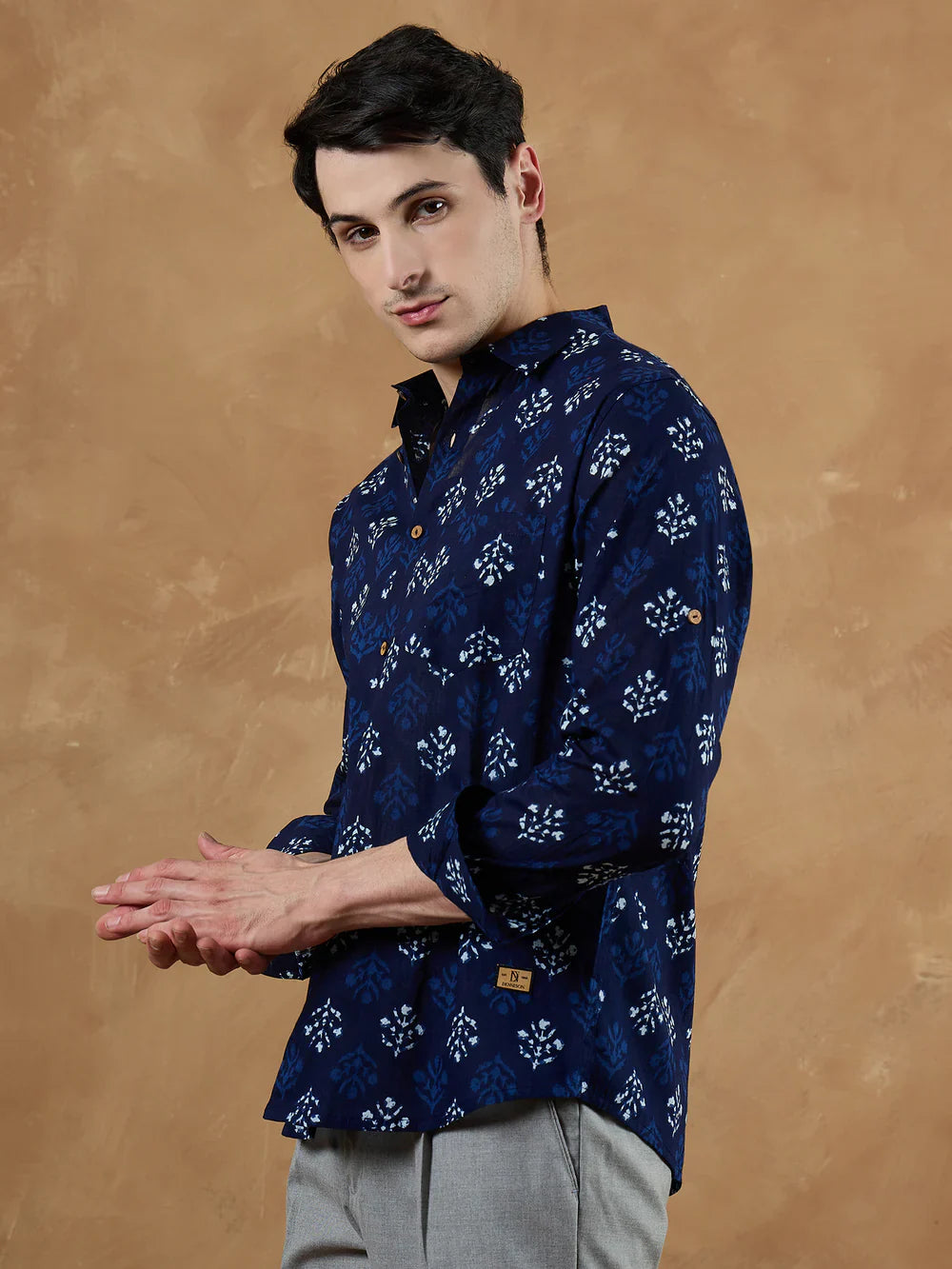Man wearing a blue patterned shirt against a brown background