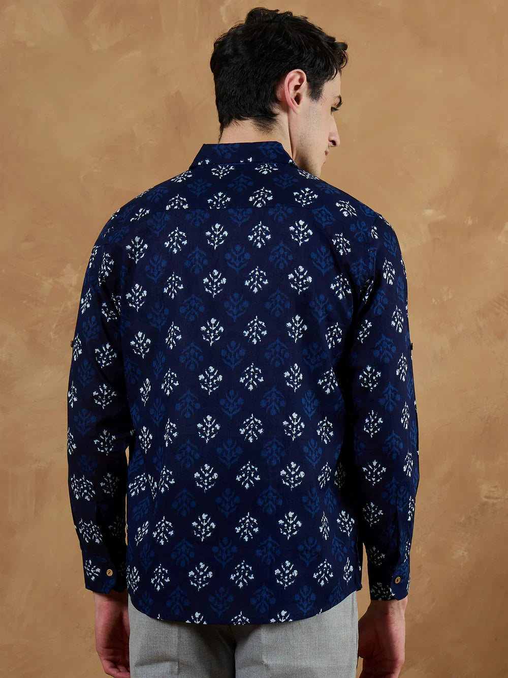 Man wearing a navy blue patterned shirt against a brown background