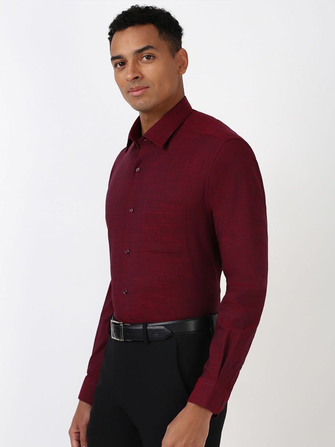 Man wearing a burgundy dress shirt and black pants on a white background