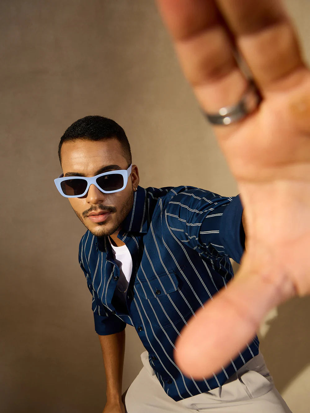 Man wearing sunglasses and a striped shirt with a blurred foreground