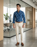 Man in a blue patterned shirt and beige pants standing in an office setting