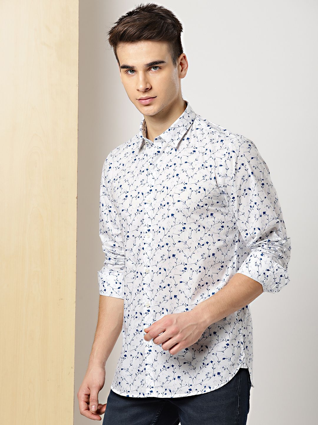 Man wearing a white shirt with black and blue pattern against a plain background