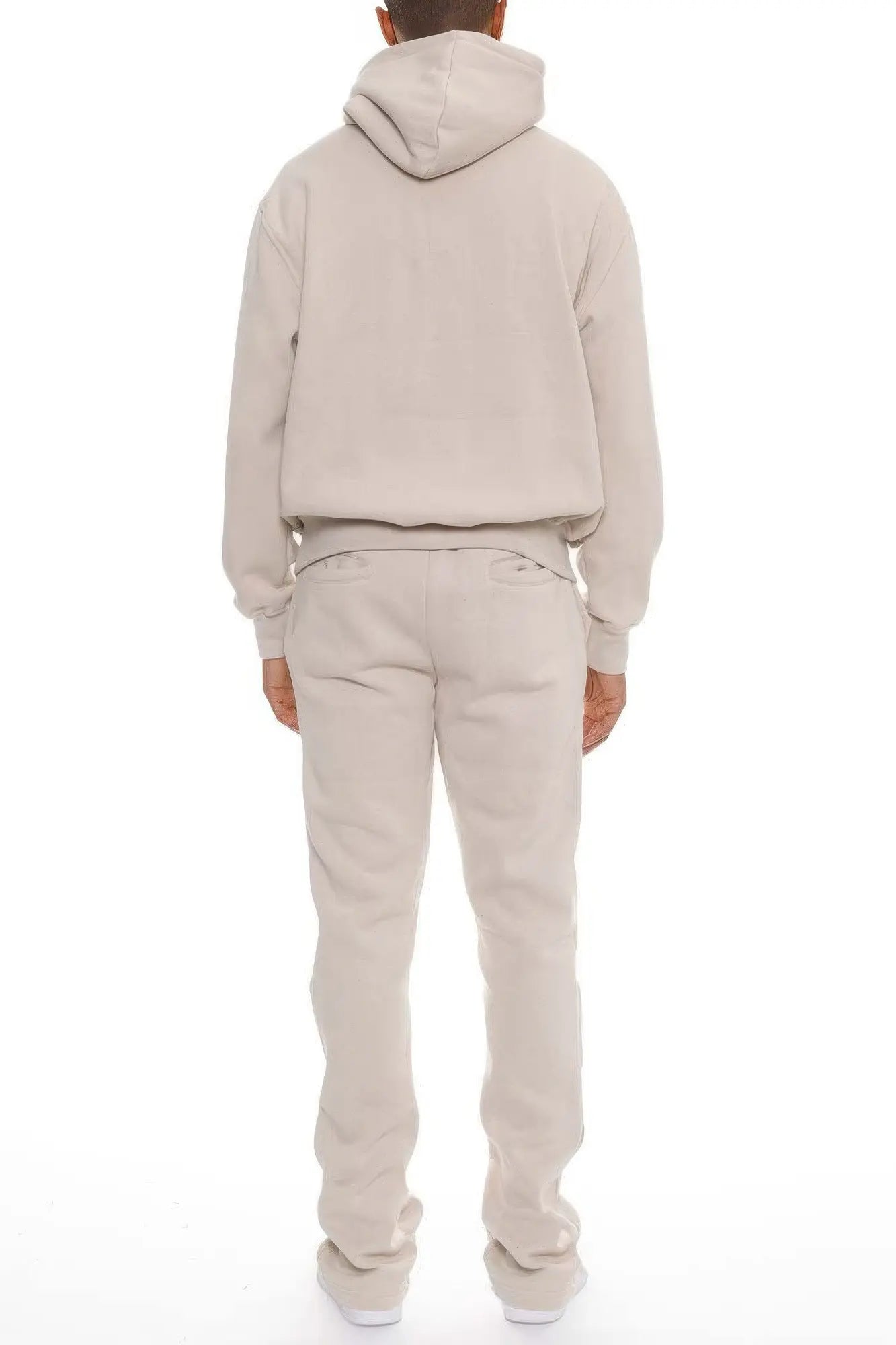 Person wearing a beige hoodie and pants set on a white background