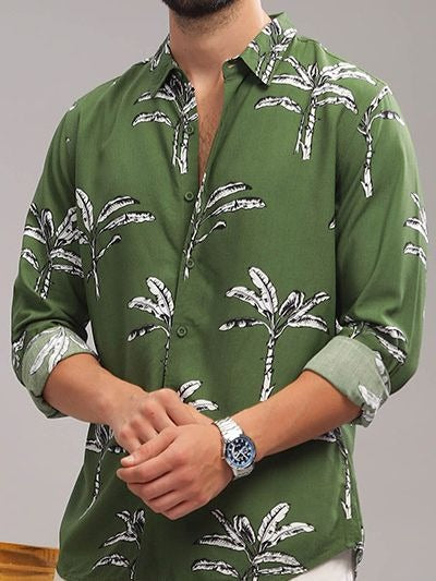 Green shirt with palm tree pattern worn by a person on a gray background