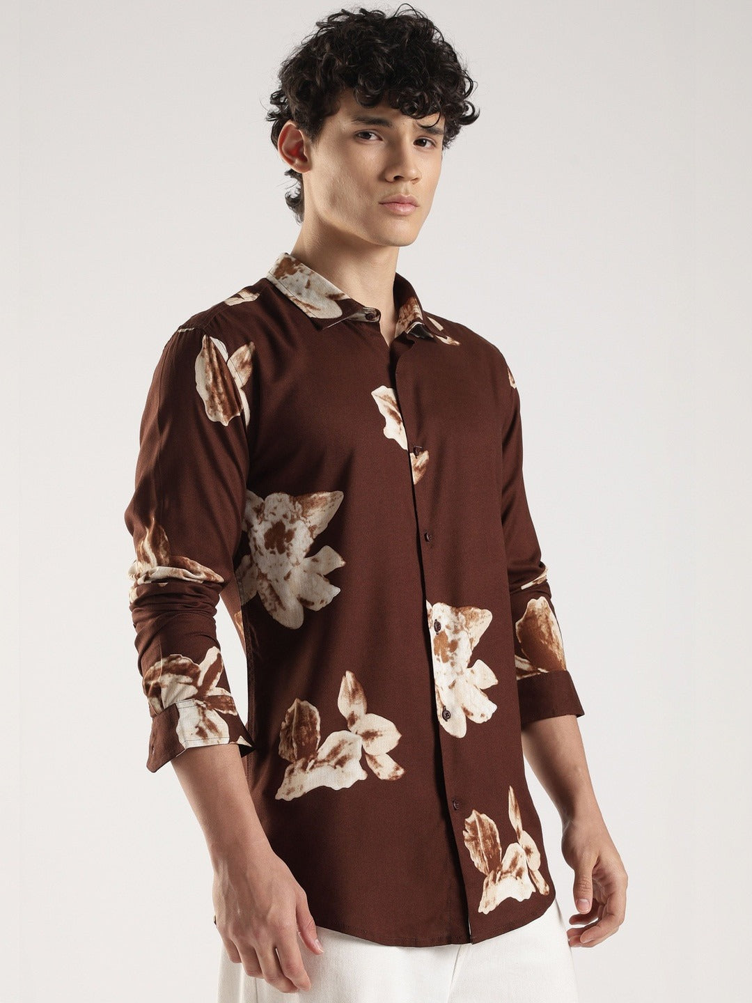 Man wearing a brown floral patterned shirt on a white background