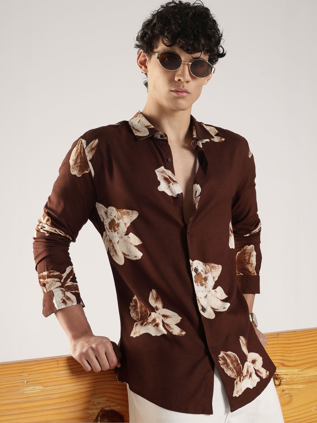 Man wearing a brown floral patterned shirt against a white background
