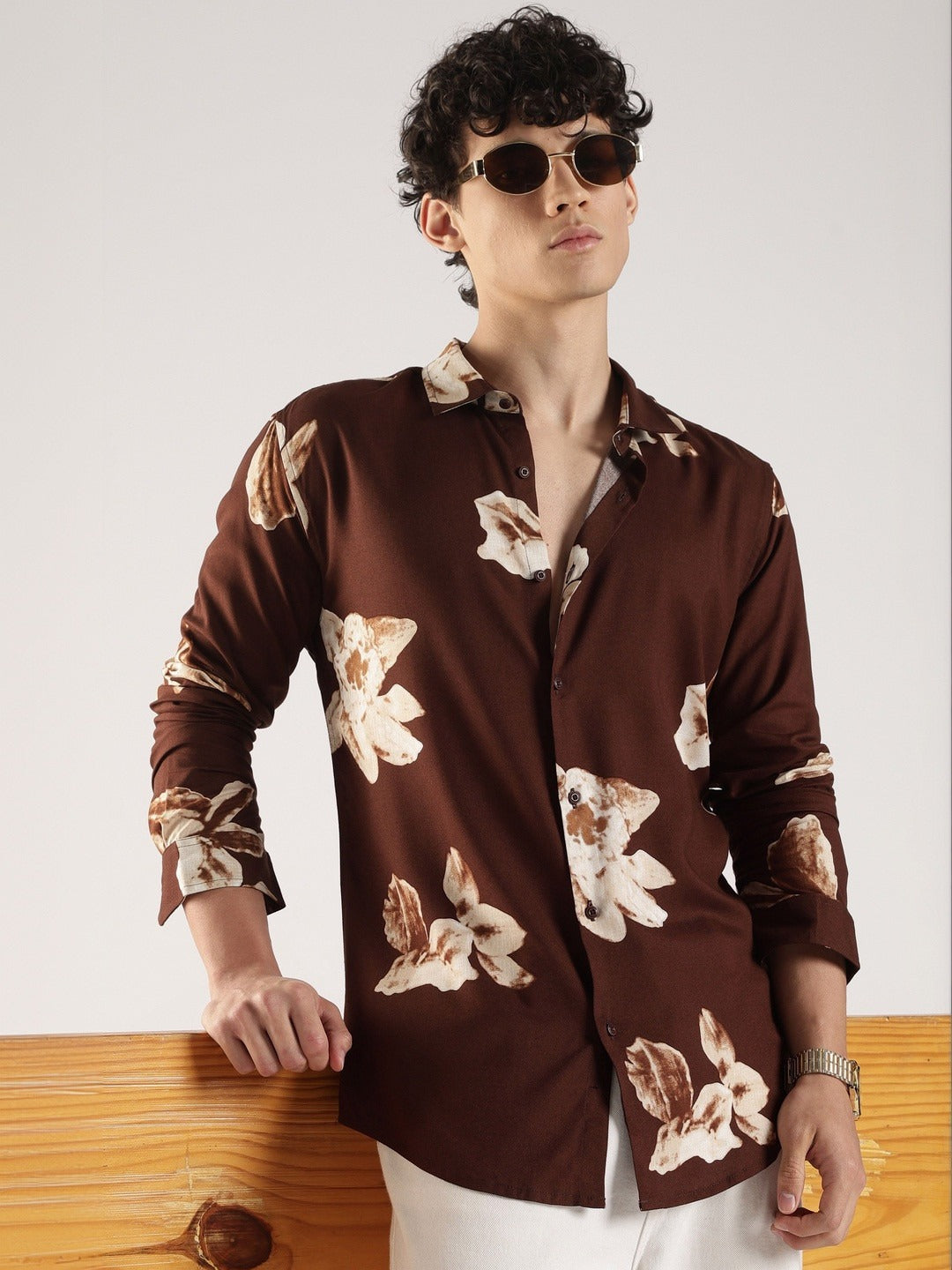 Man wearing a brown floral shirt against a white background