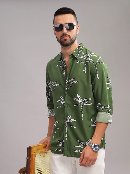 Man wearing a green shirt with palm tree pattern against a gray background