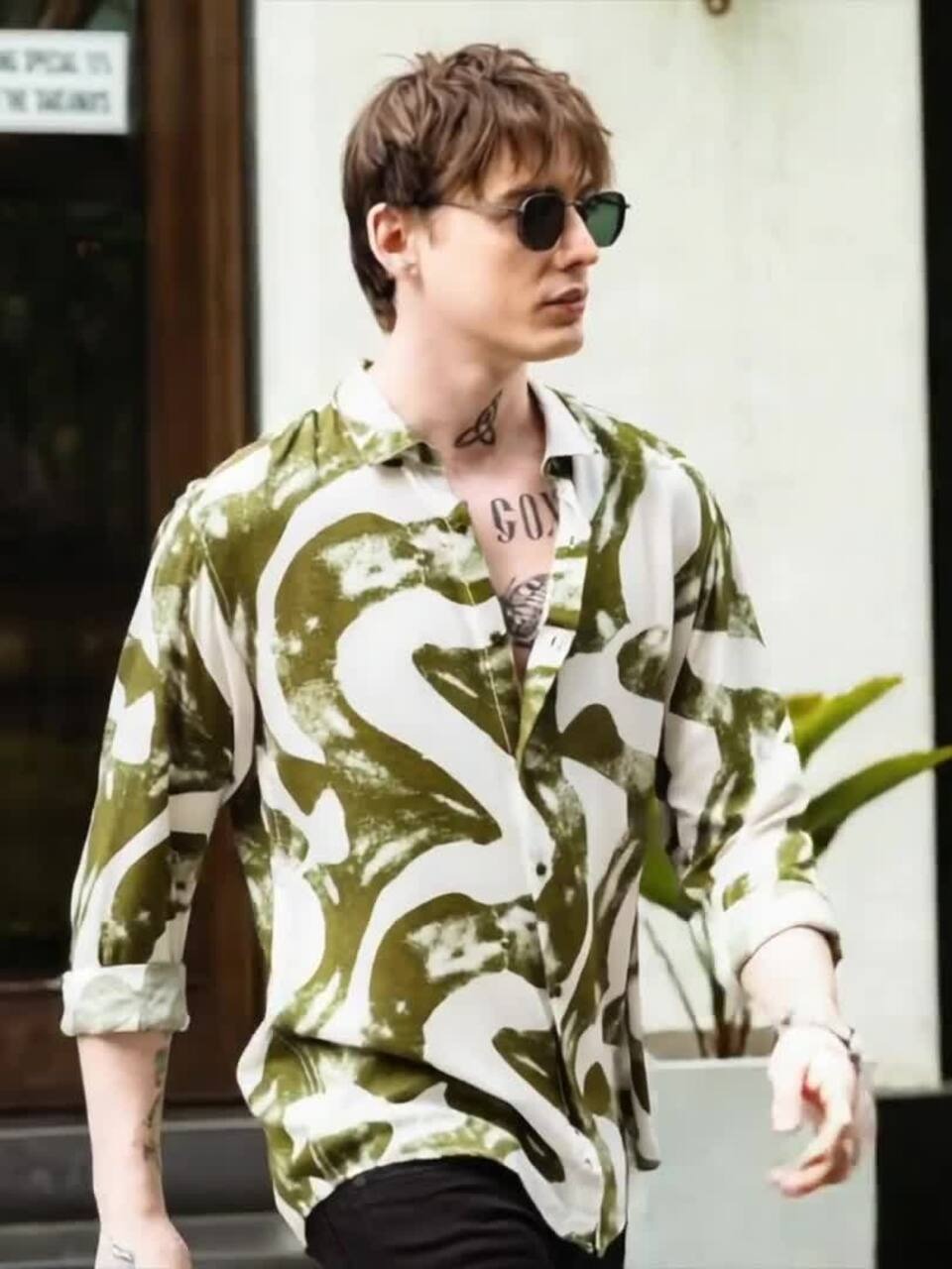 Person wearing a green camouflage-patterned shirt with a brand logo.