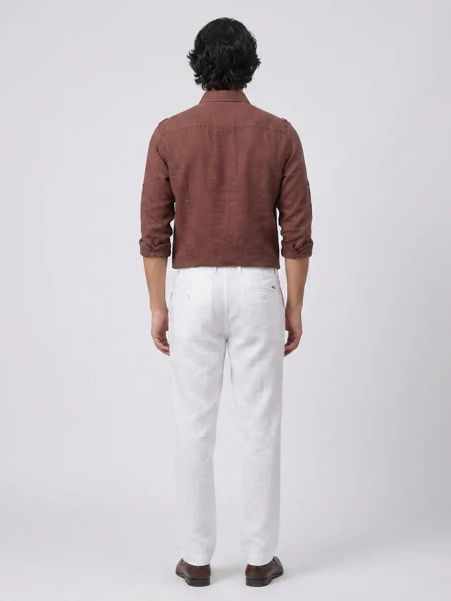 Man wearing a brown shirt and white pants on a white background