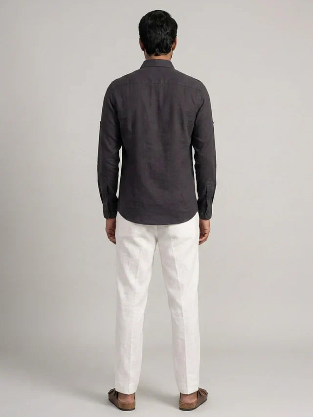 Man wearing a dark gray shirt and white pants on a light gray background
