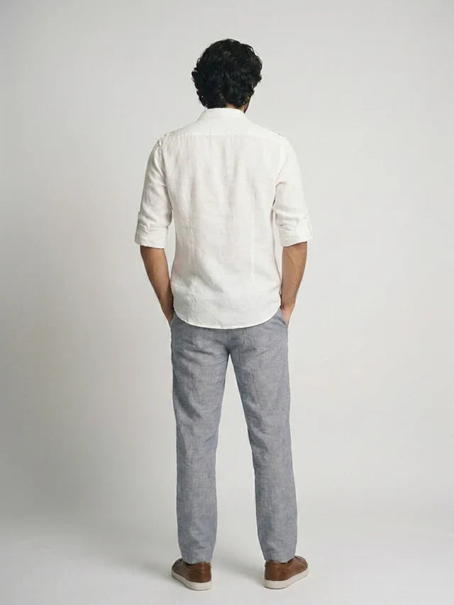 Person wearing a white shirt and gray pants on a plain background