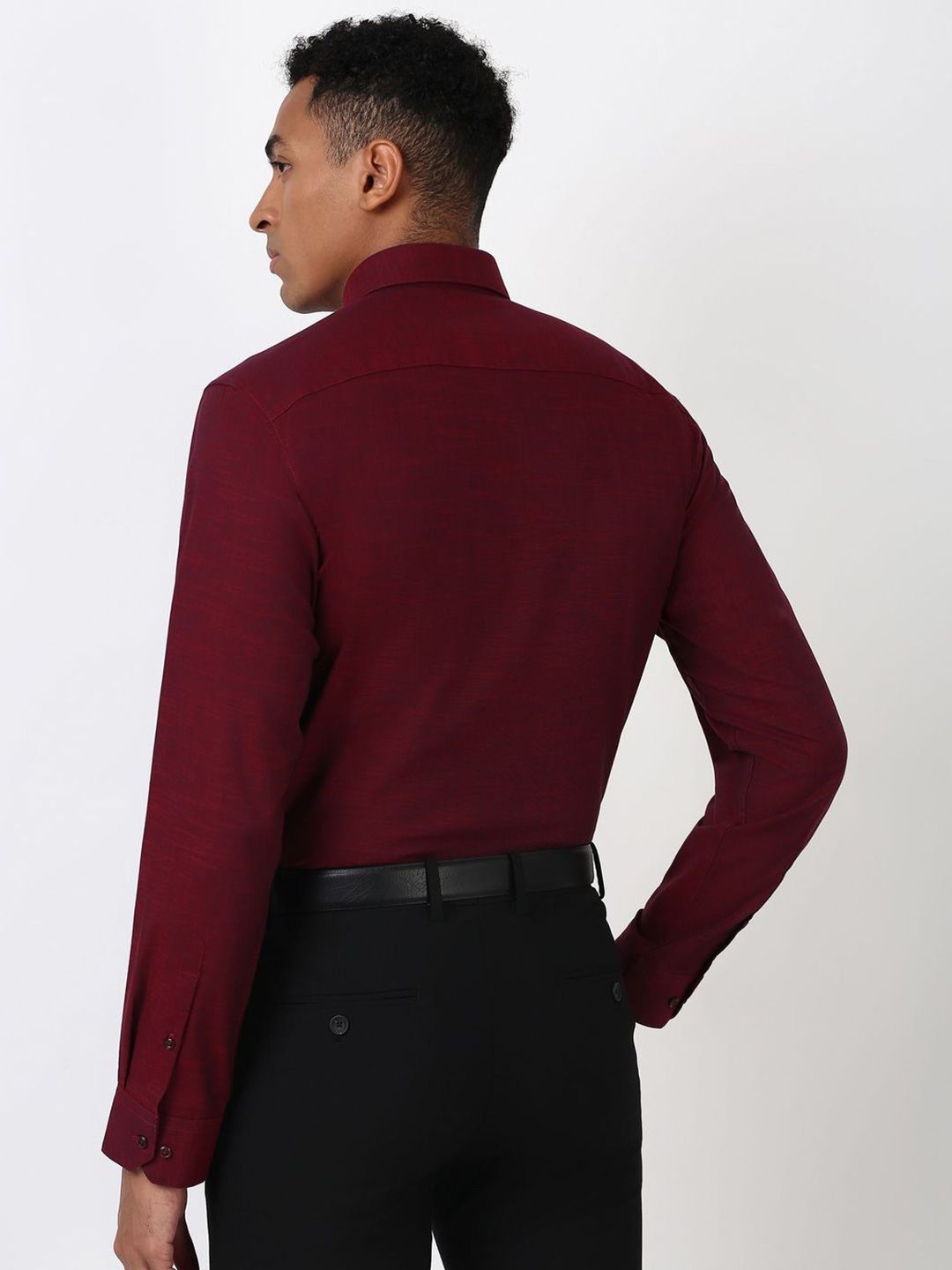 Person wearing a burgundy dress shirt and black pants on a white background