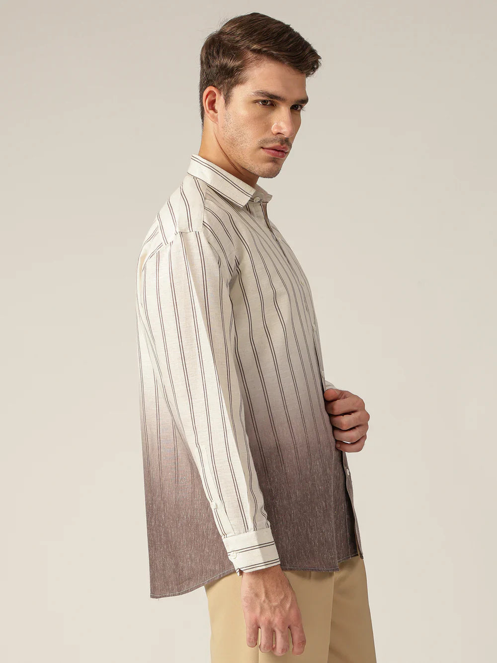 Man wearing a striped shirt with a gradient effect from beige to brown on a neutral background