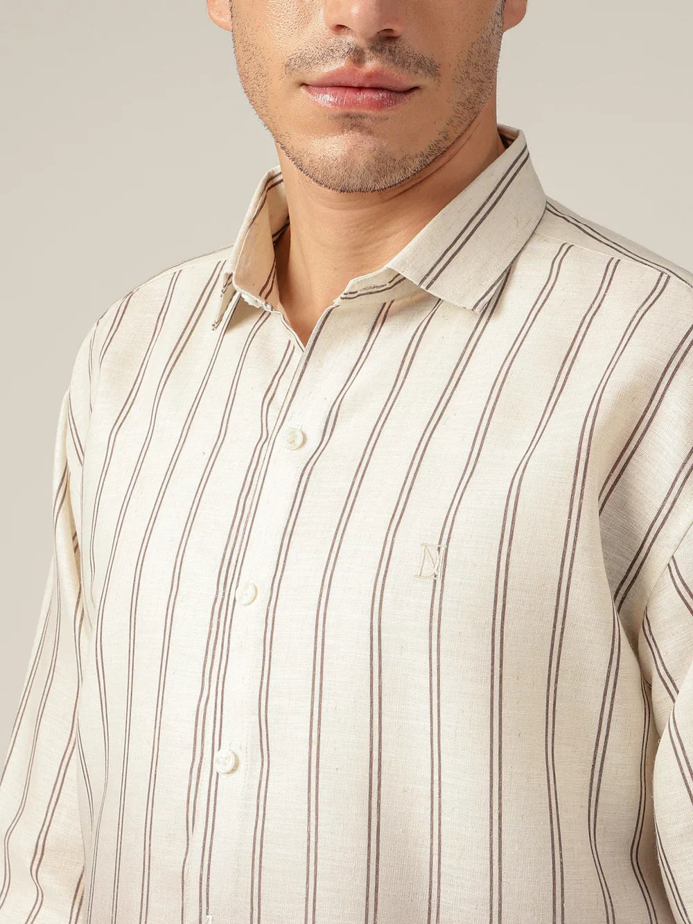 Man wearing a beige and brown striped shirt against a plain background