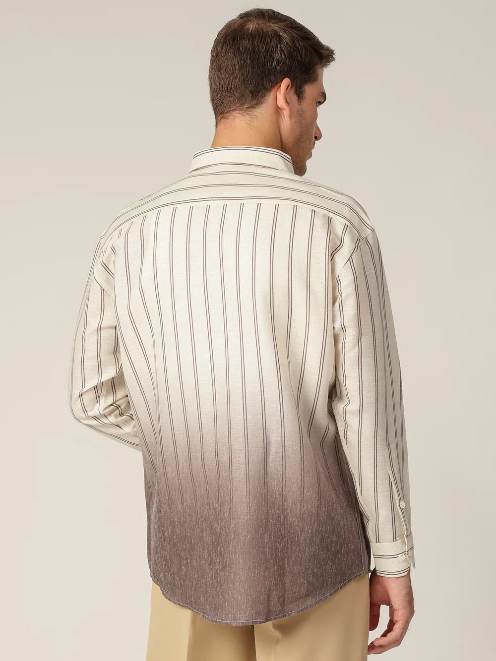 Man wearing a striped shirt with a gradient effect on a plain background