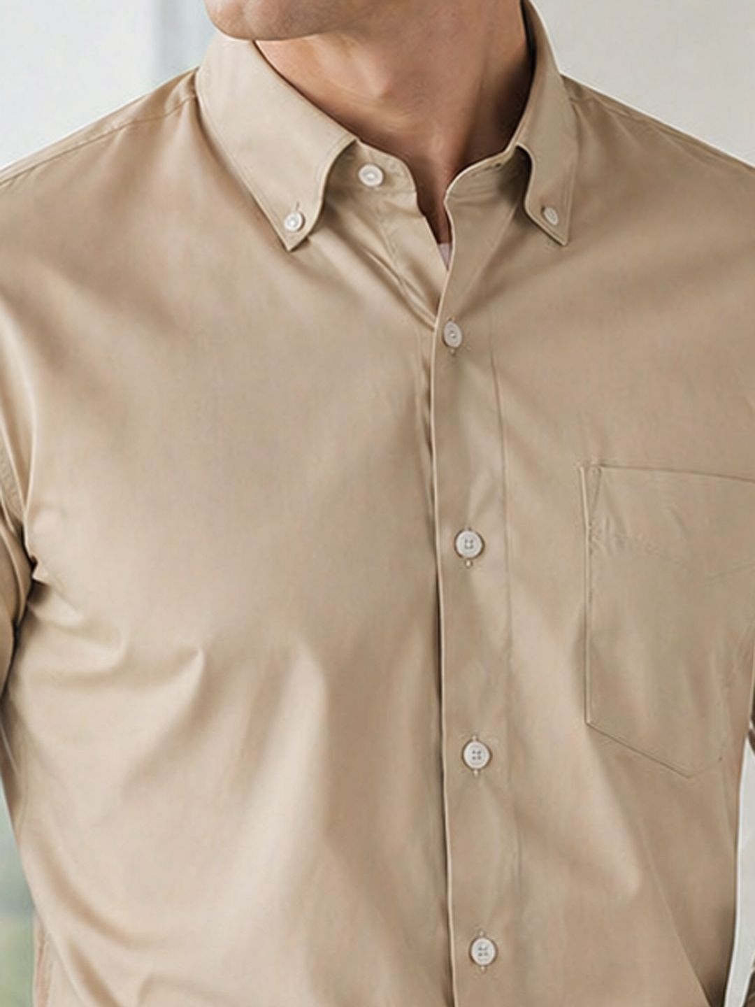 Close-up of a beige button-up shirt worn by a person.