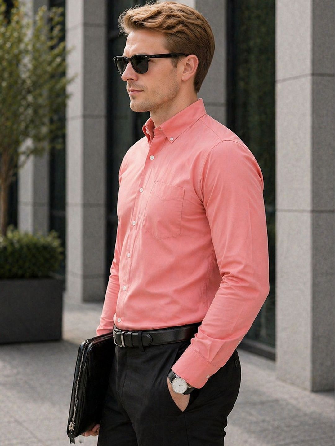 Man wearing a pink shirt and sunglasses, standing outdoors.