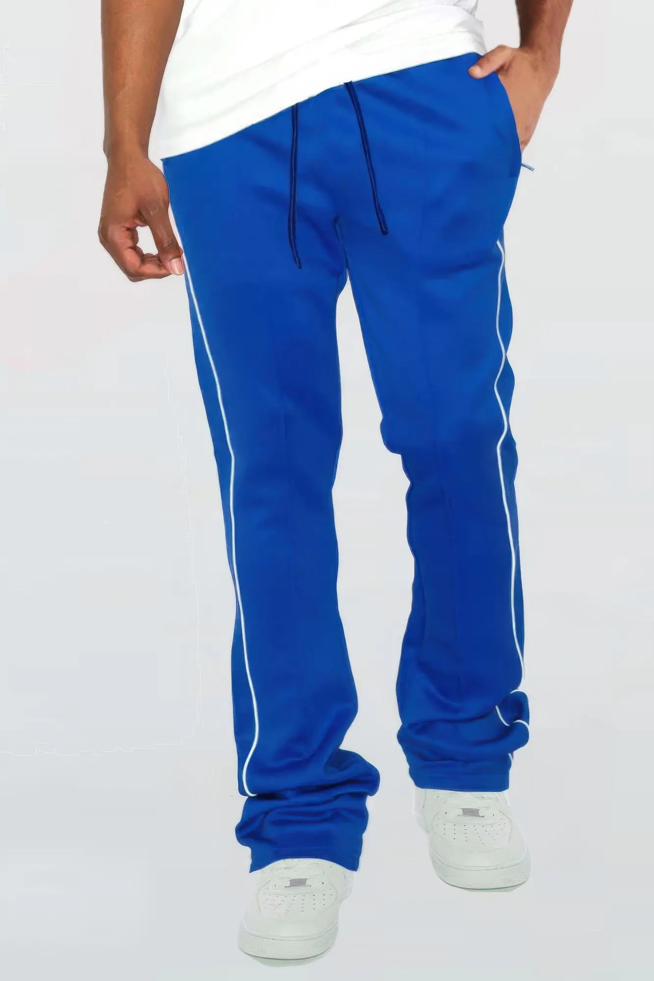 Blue track pants with white stripes worn by a person on a white background