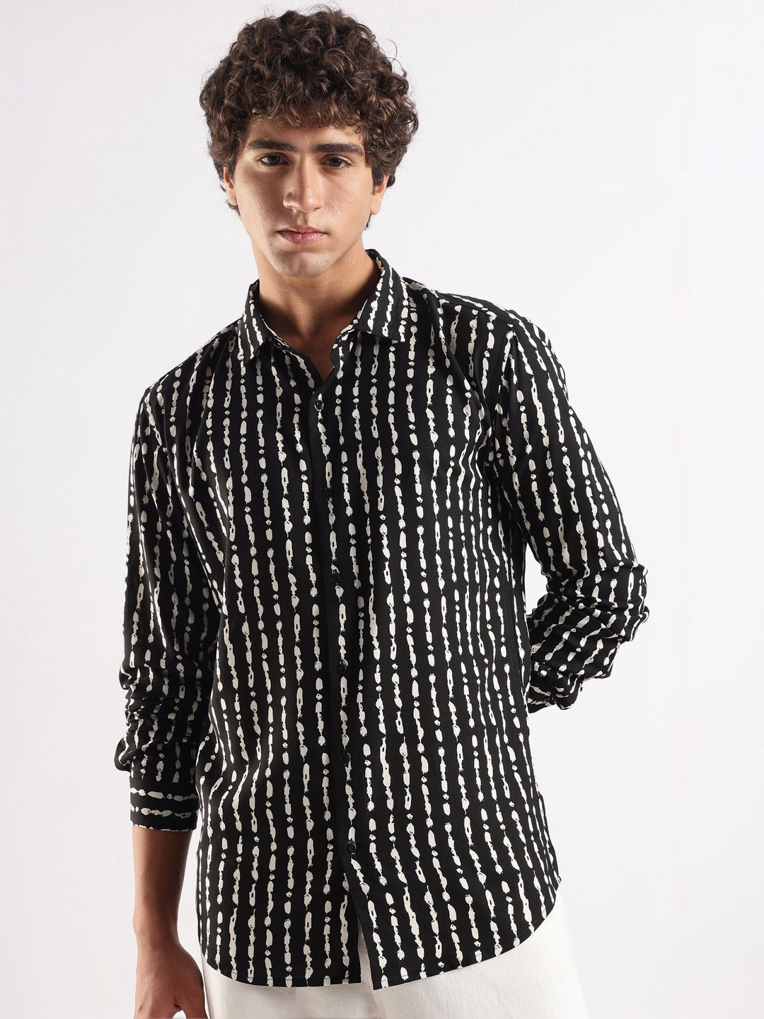 Man wearing a black and white patterned shirt on a white background