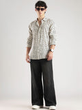 Man wearing a patterned shirt and black pants on a white background