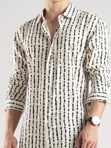Man wearing a white shirt with black pattern on a plain background