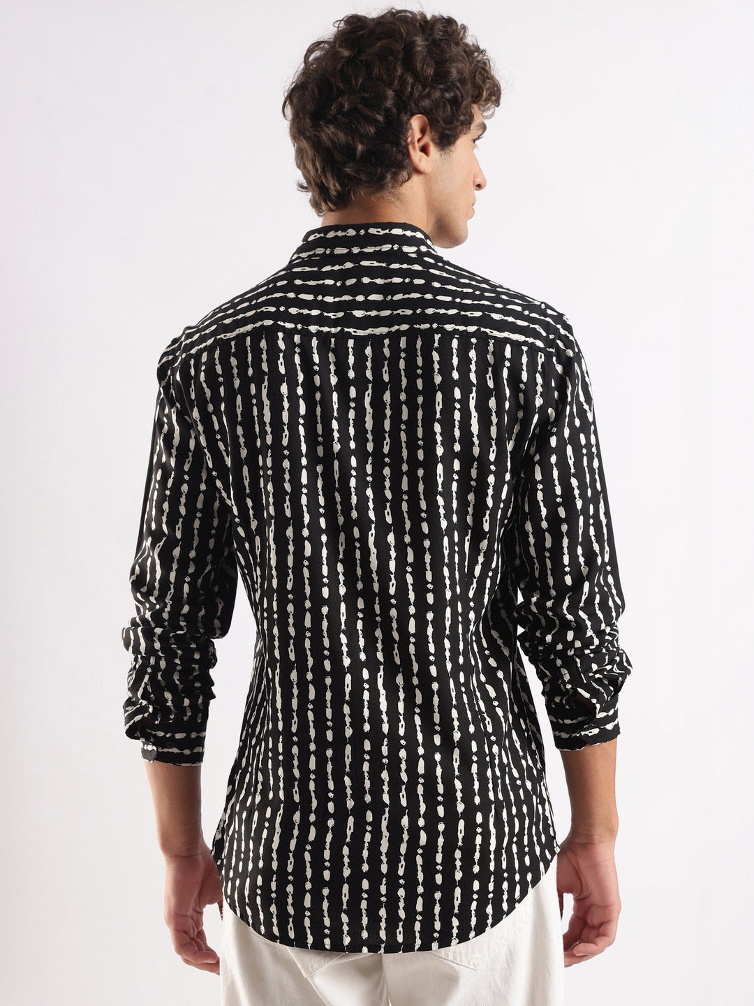 Man wearing a black and white patterned shirt on a white background