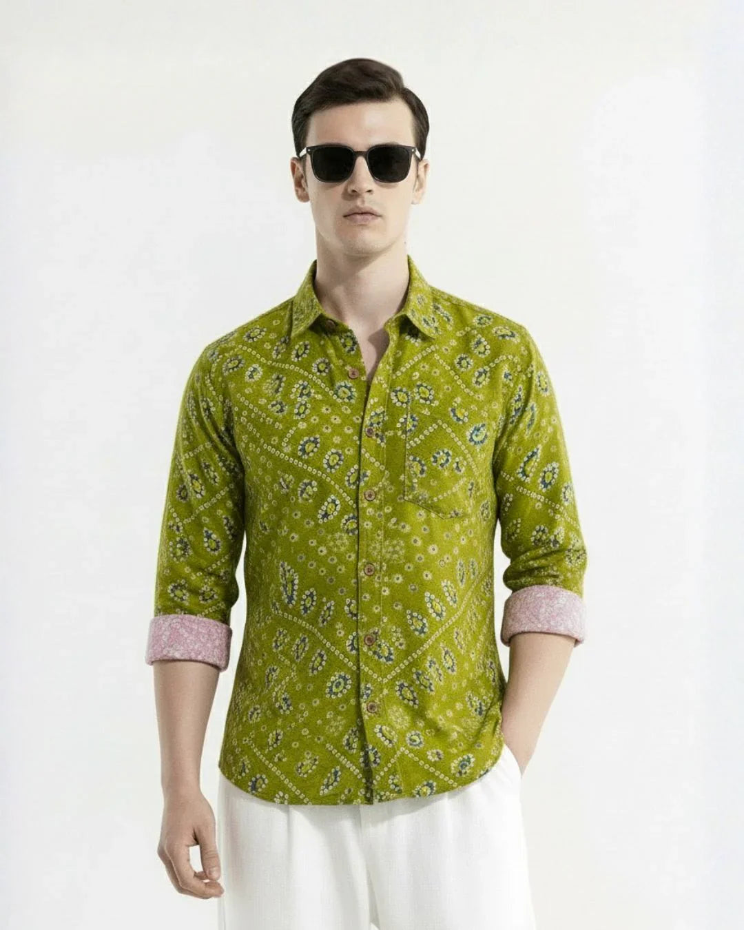 Man wearing a green patterned shirt and sunglasses on a white background