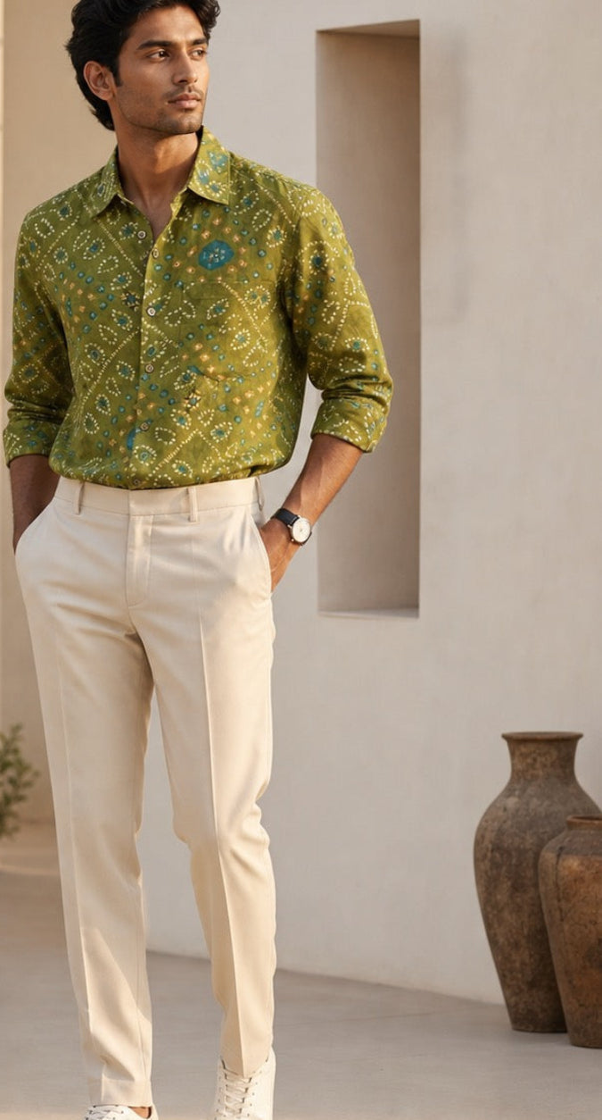 Man wearing a green patterned shirt and beige pants in a minimalistic room.
