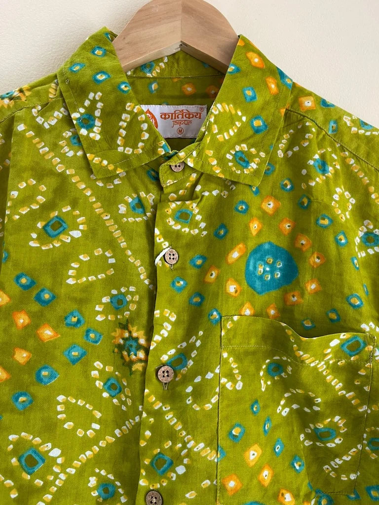 Green patterned shirt on a wooden hanger against a white background