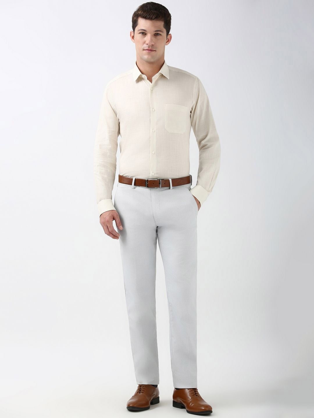 Man wearing a beige shirt, white pants, and brown shoes on a white background
