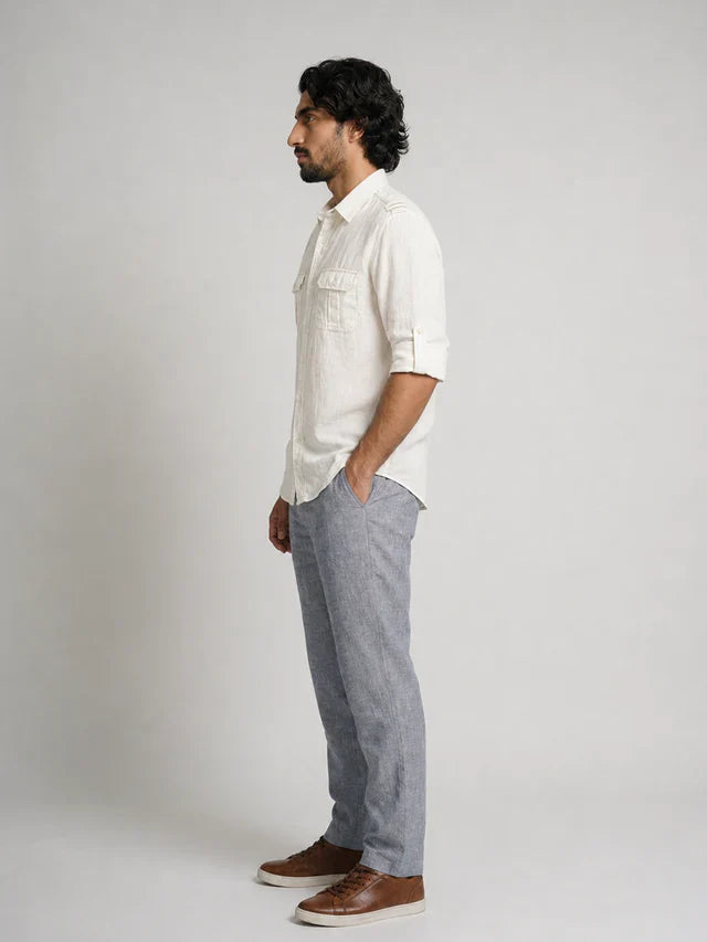 Man wearing a white shirt and gray pants standing against a plain background