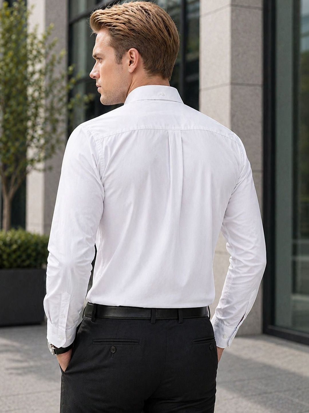 Man wearing a white dress shirt and black pants standing outdoors.