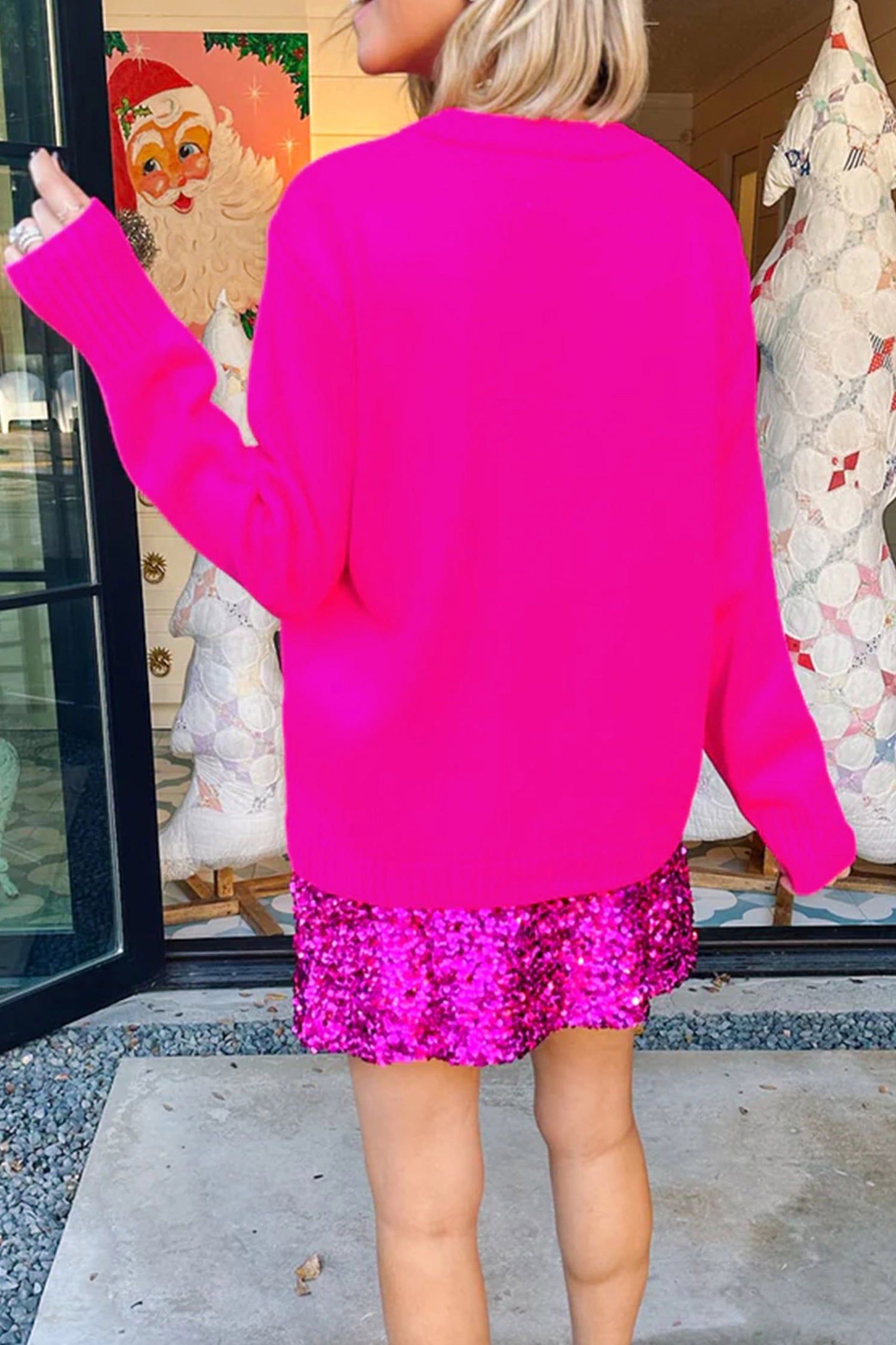 Back view of woman in hot pink sweater and matching sequin mini skirt.
