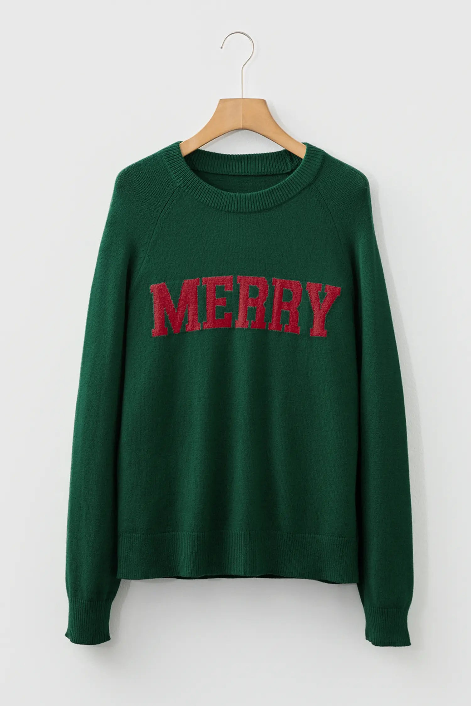 Green sweatshirt with 'MERRY' in red on a hanger against a white background