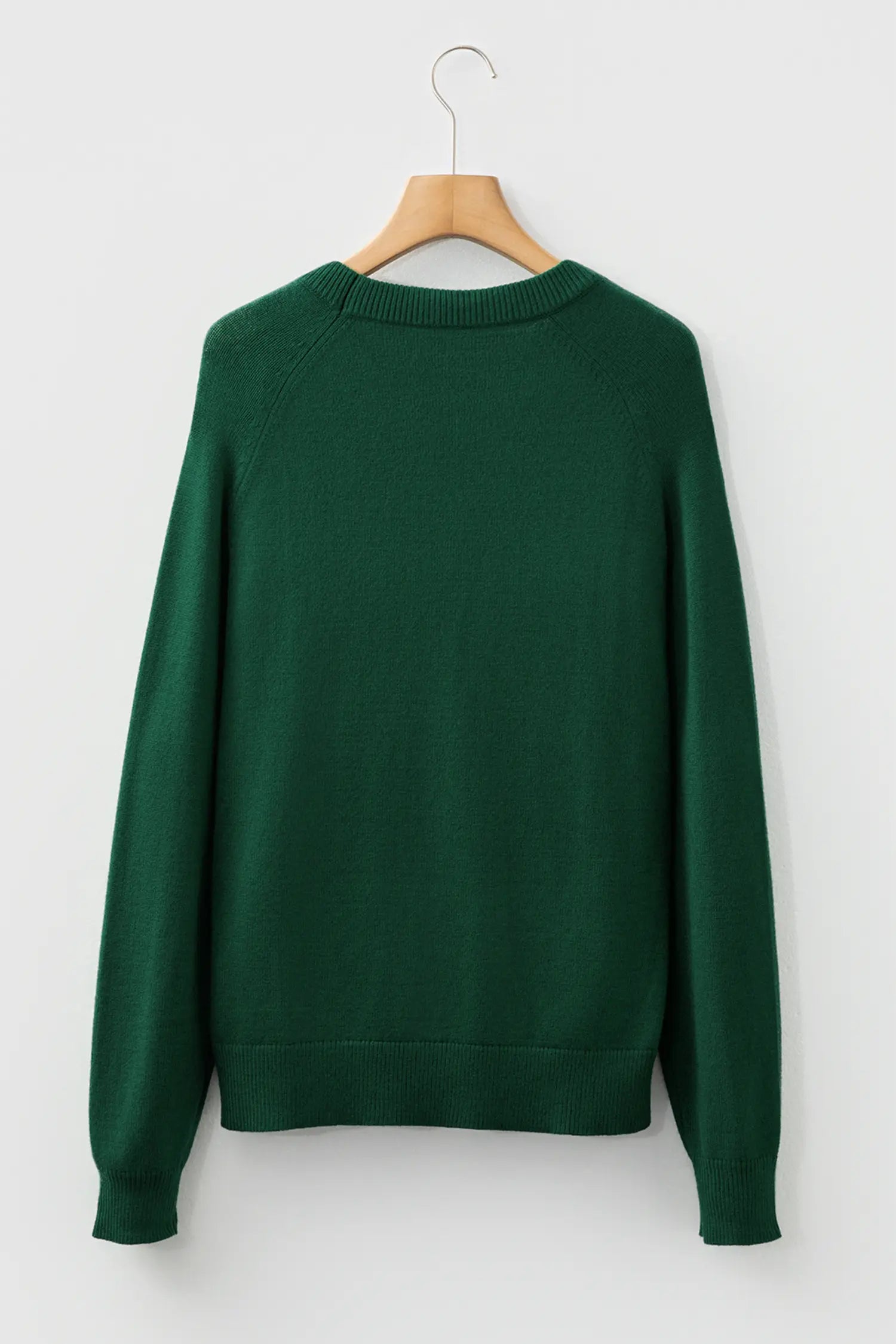Green sweater on a wooden hanger against a white background