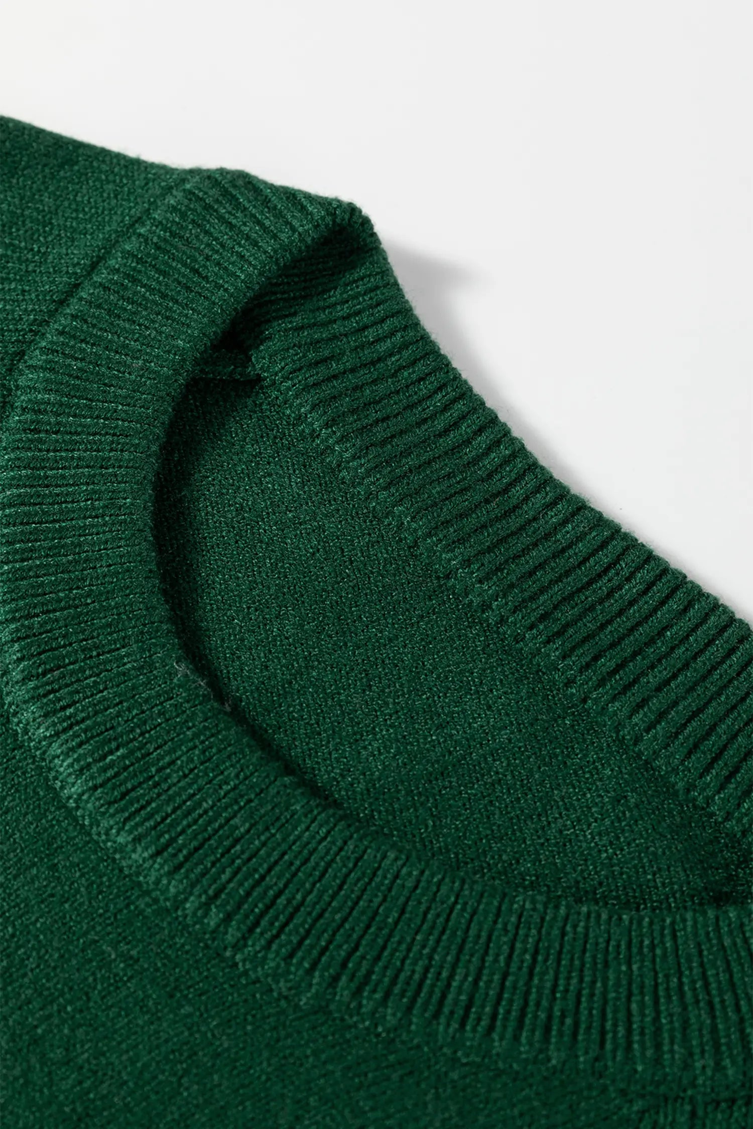 Close-up of a dark forest green ribbed knit garment, showing the neckline and collar detail against a plain white background.