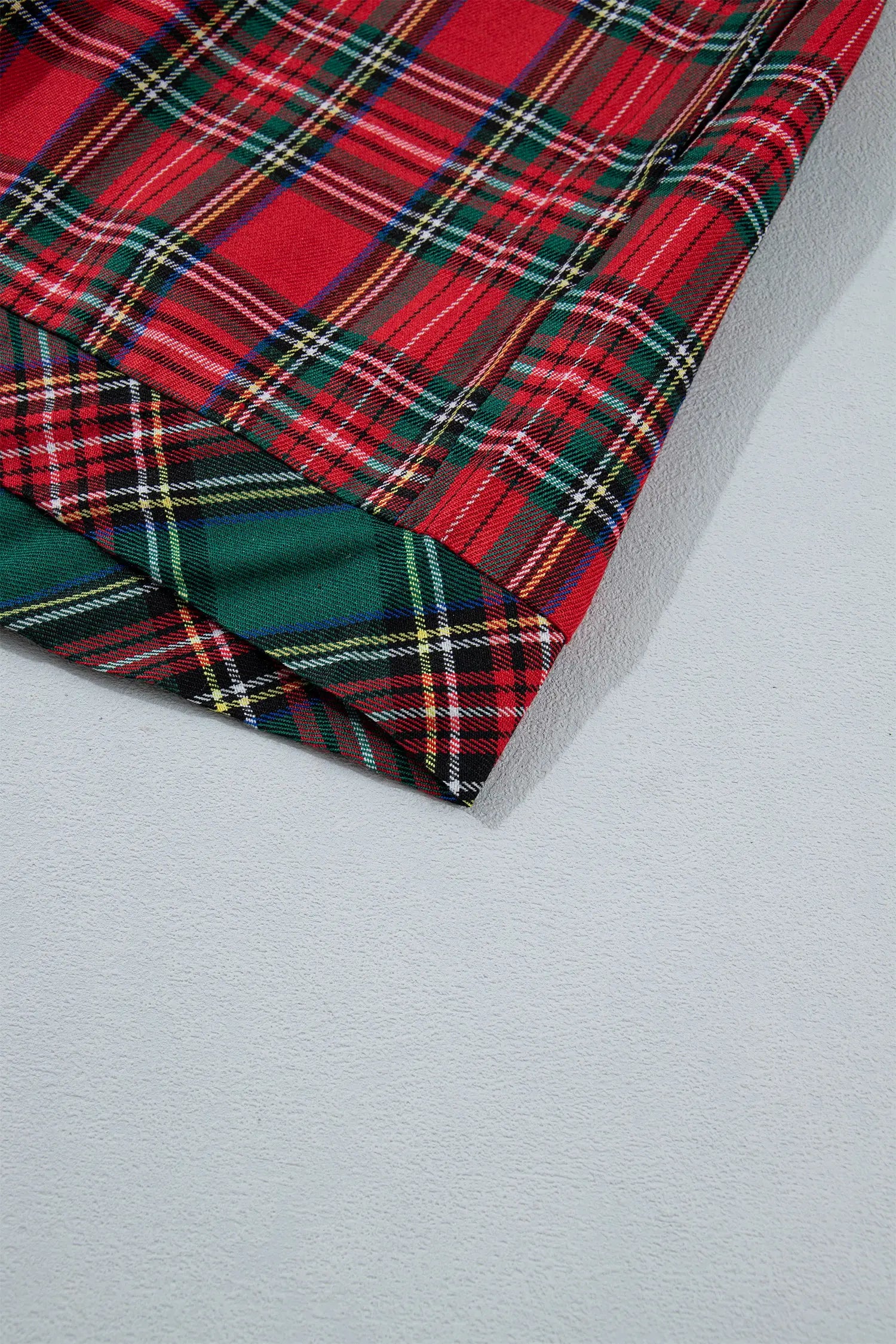 Close-up of folded tartan fabric with red, green, black, and yellow plaid.