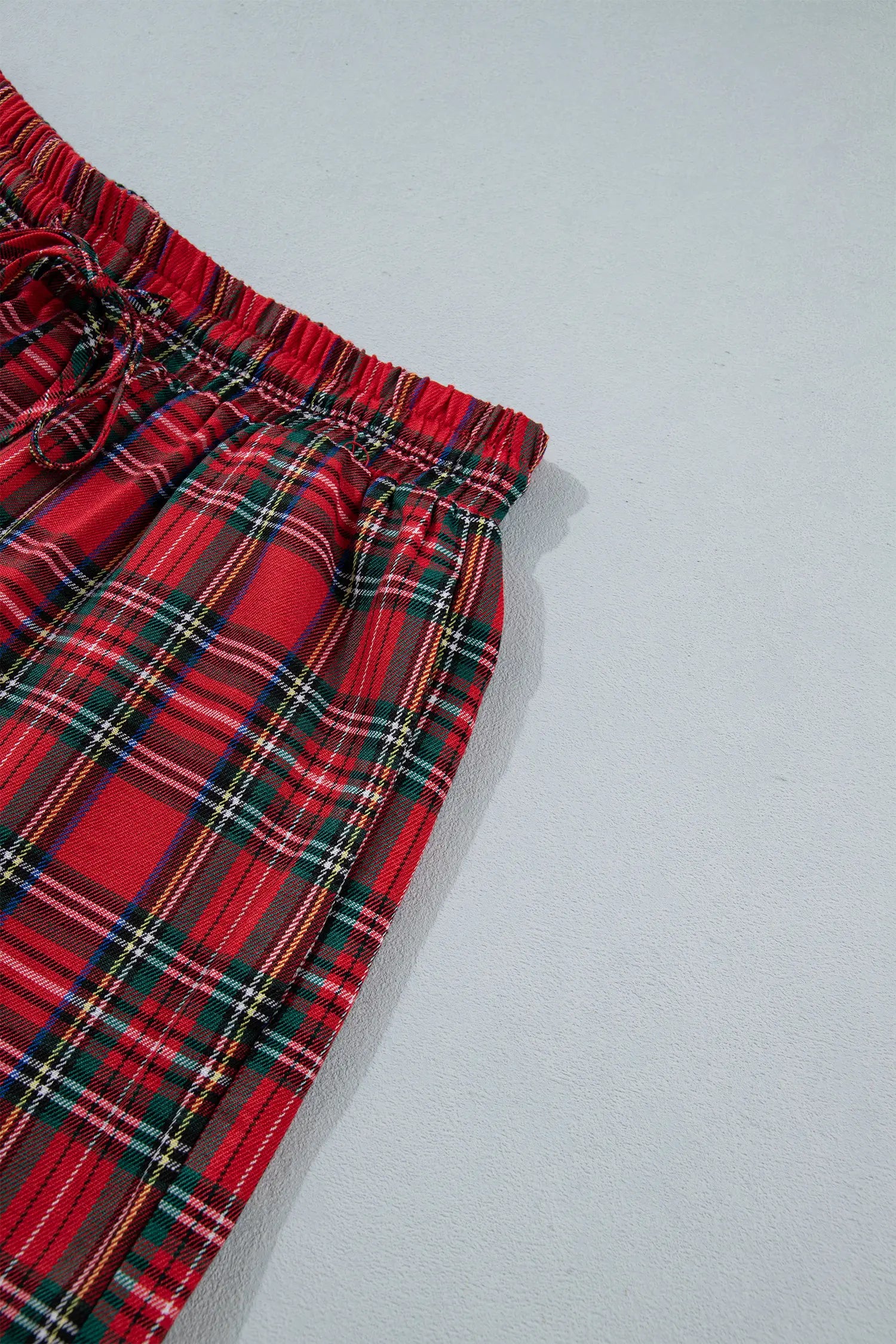 Close-up of red plaid drawstring pants with green, white, and yellow stripes.