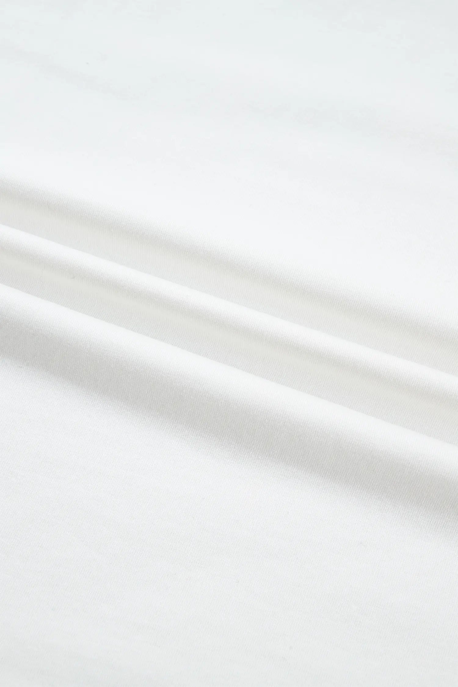 A close-up of white fabric with soft folds and a smooth texture.