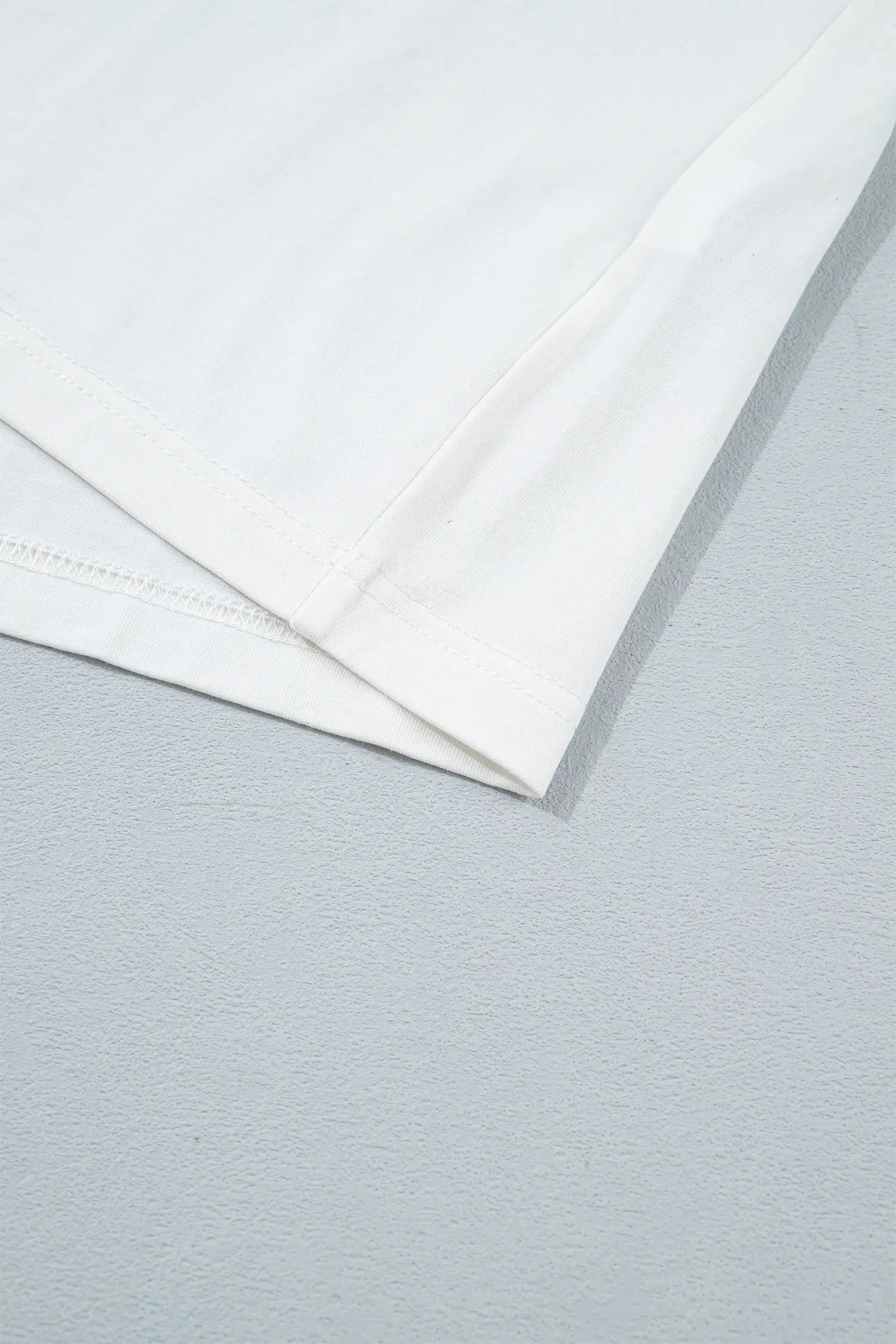 Close-up of folded white fabric showing hem and clean stitching.