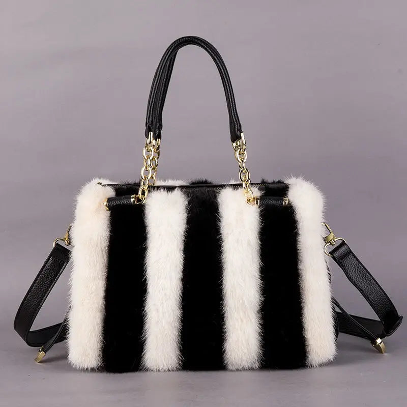 Black and white striped handbag with fur trim on a gray background
