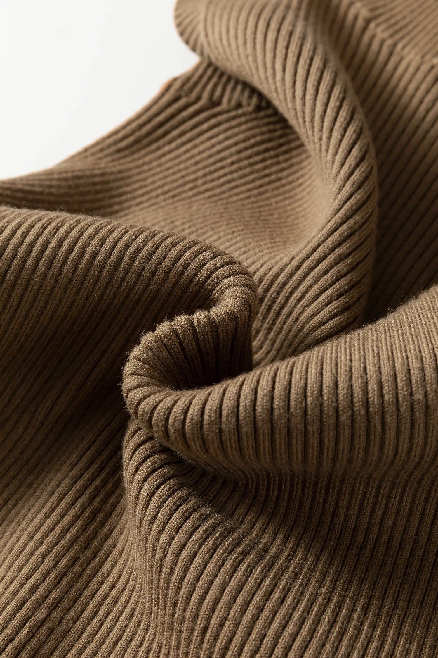 A close-up of a brown ribbed knit fabric, showing the detailed texture and folds of the material against a clean white background.