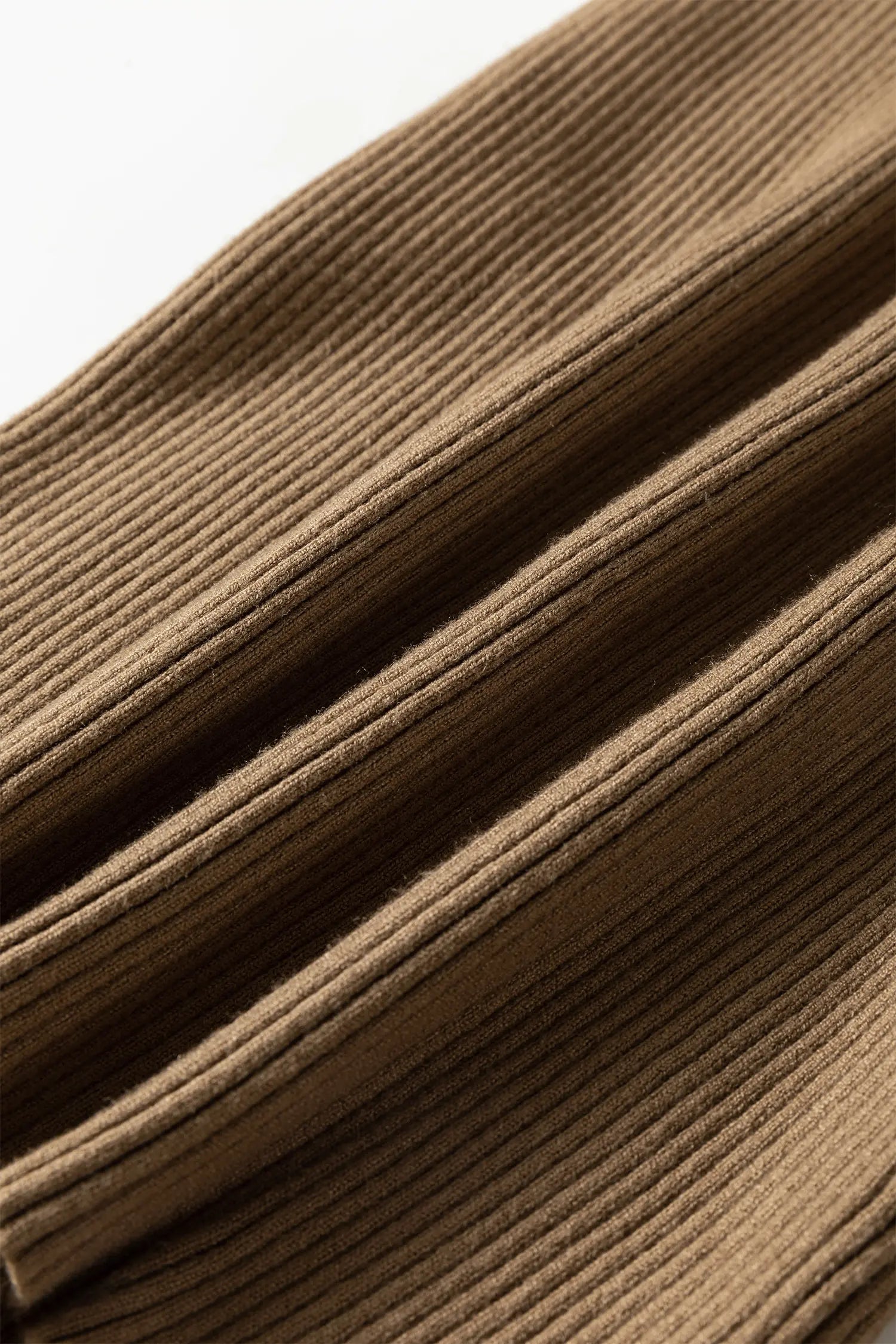 A close-up of a brown ribbed knit fabric, showing the detailed texture and folds of the material.