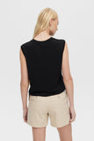 Woman wearing a black sleeveless top and beige shorts on a white background
