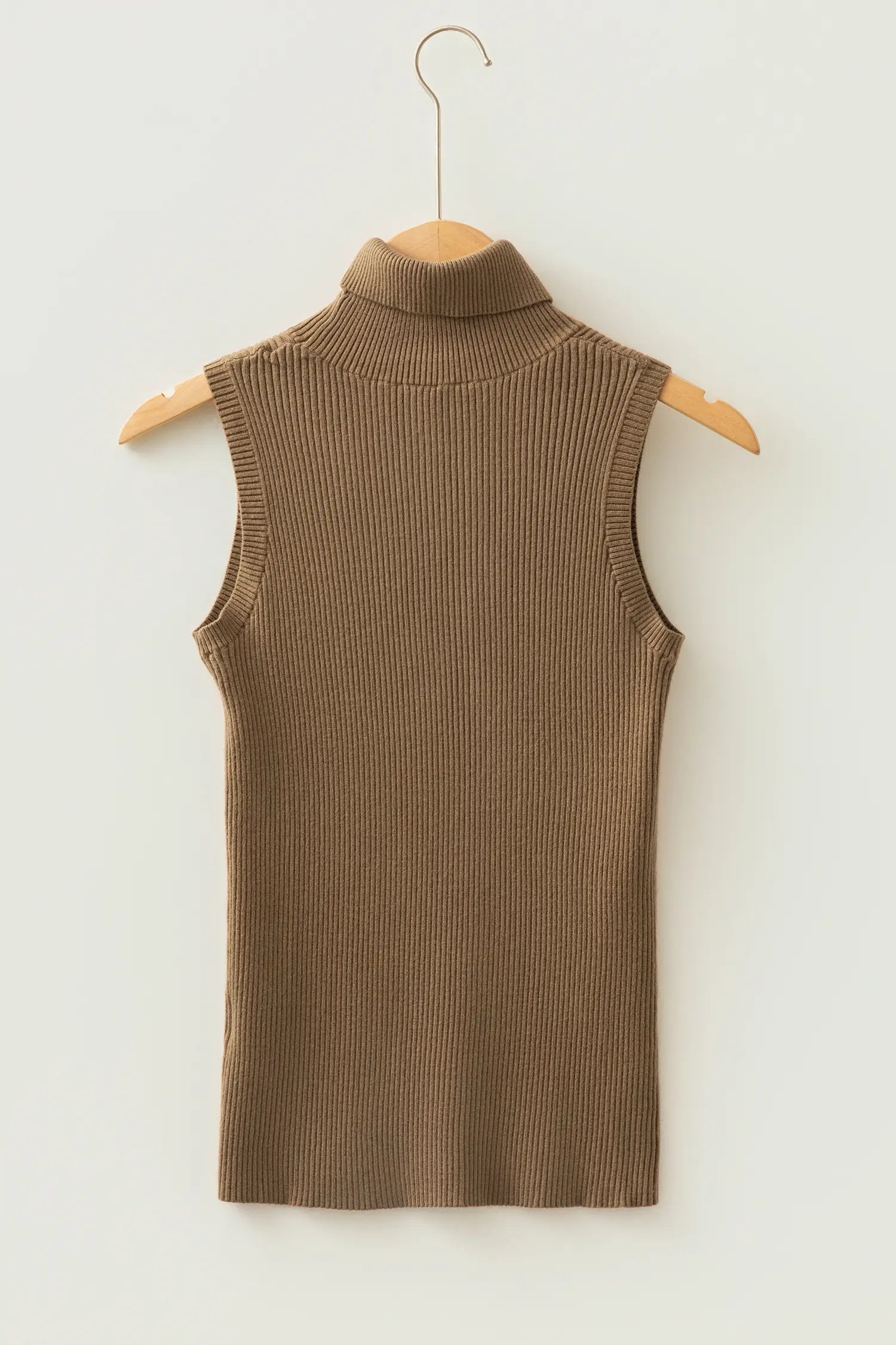 A sleeveless ribbed knit mock neck top in a warm taupe-brown color, hanging on a wooden hanger against a plain off-white wall.