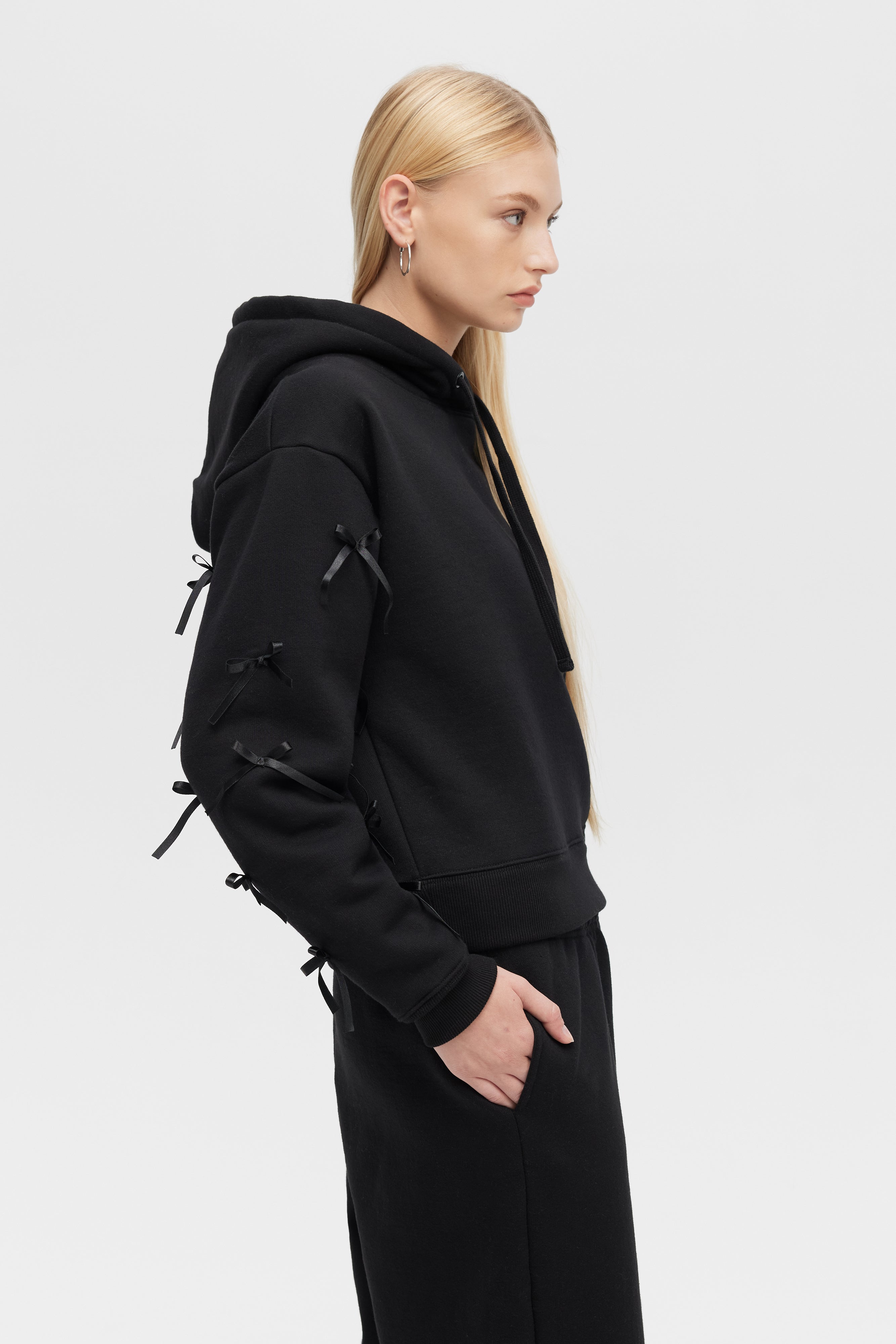 Person wearing a black hoodie and pants on a white background