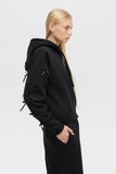 Person wearing a black hoodie and pants on a white background